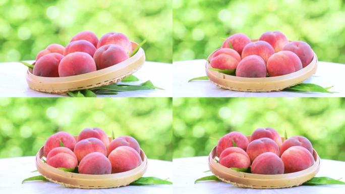 模糊花园背景中的粉红色和黄色桃子水果，花园木桌上的竹篮中的白色桃子。
