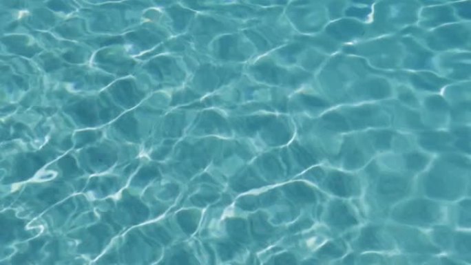阳光照射的游泳池的绿松石表面。抽象反射和折射光