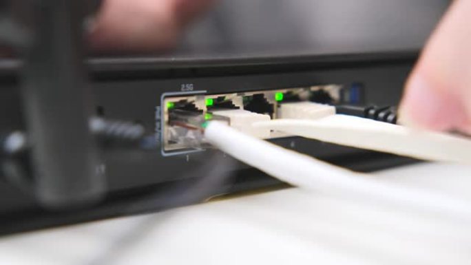 女人的手将互联网电缆连接到局域网有线网络交换机。互联网通信和计算机技术概念。