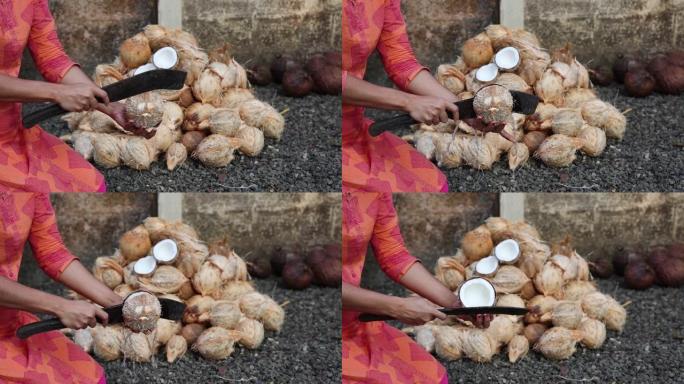 女人用刀打碎新鲜的生有机椰子，切成半椰子水飞溅