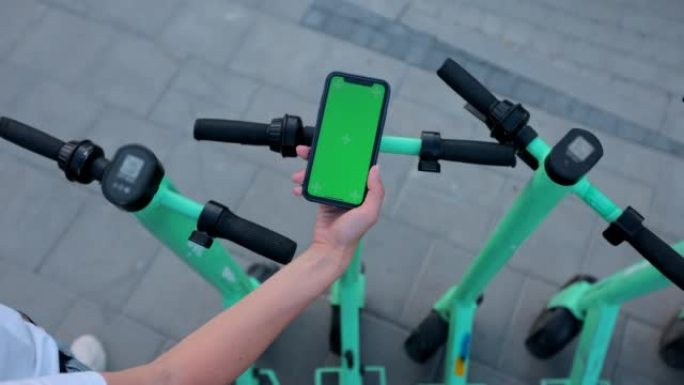 公共公园电动滑板车背景上的女人手点击手机，模型，chromakey。城市风情骑行生态交通。