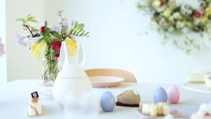 一个美丽的复活节装饰，上面有一束春天的鲜花，蛋形蜡烛，旁边是糕点店的现代蛋糕