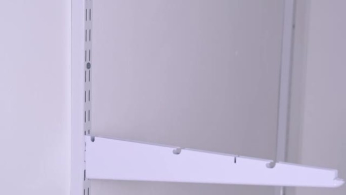 更衣室系统中金属网架的安装支架在支架上。Hands正在组装白色支架存储系统特写