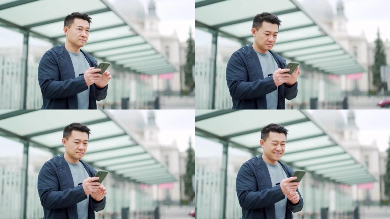 高级中国游客使用手机应用程序预订住宿和叫出租车，男子在机场附近带着行李箱。亚洲男子使用智能手机应用程