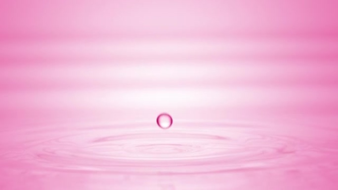 粉红色液体滴落在液体表面上，形成圆圈