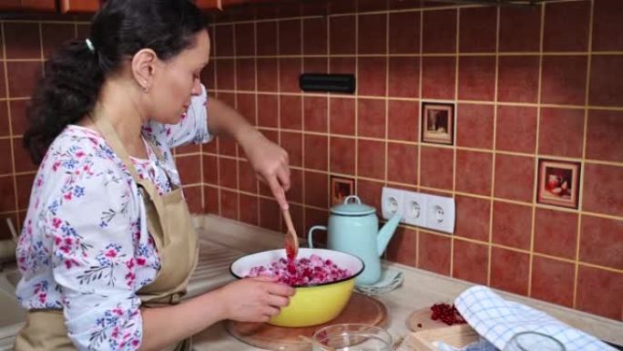 女厨师糖果用木勺搅拌撒上糖的红醋栗，准备自制果冻