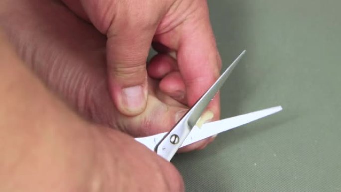 金属剪刀在大脚趾上剪指甲的特写。