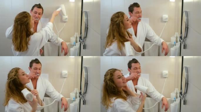 穿着浴袍的年轻夫妇在镜子前的浴室里一起清洁牙齿。