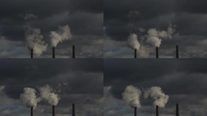 来自热电联产厂的三个烟囱的特写镜头，在多云的天空中。全球变暖、环境灾难和使用不可持续燃料的概念