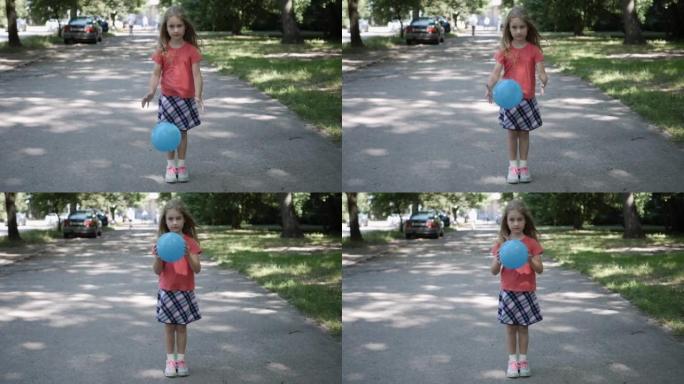 夏天，肖像小女孩站在城市的街道上看着相机。孤独的孩子在空荡荡的城市街道中间玩球。慢动作。社会发展注意