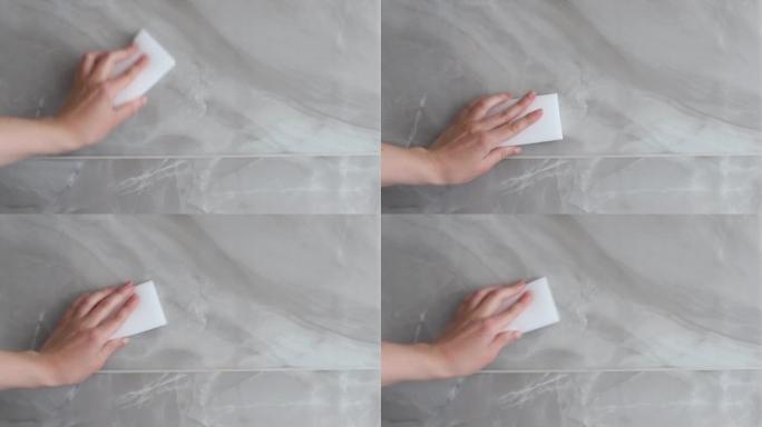 一名妇女用三聚氰胺海绵擦拭瓷砖表面。特写