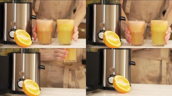 一个女人的手拿着两杯在榨汁机中准备的新鲜果汁。葡萄柚和橙汁是健康食品，是节食和排毒身体的水果。在高温