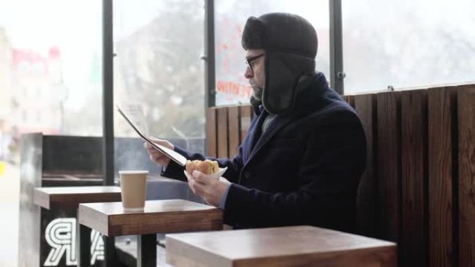 一位老人在城市里享受着寒冷的冬日早晨。一名男子坐在广场的长椅上，看报纸，兴高采烈地用手机与朋友聊天。