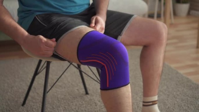 一名男子运动员受伤后的特写坐在椅子上拉着膝盖上的绷带。运动损伤的概念