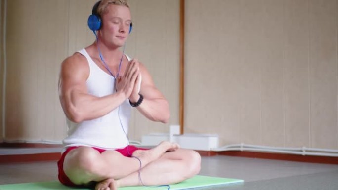 一个男人在健身房锻炼后放松的视频。健美运动员在智能手机上打开轻松的音乐并冥想