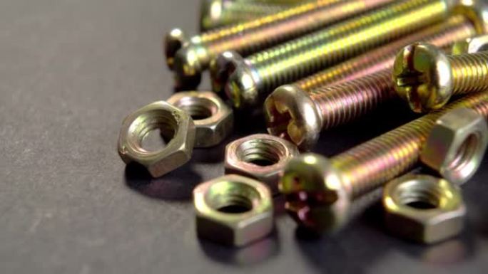 深色纸上闪亮的金属螺栓和螺母。一套用于紧固的螺纹五金件。机械工具