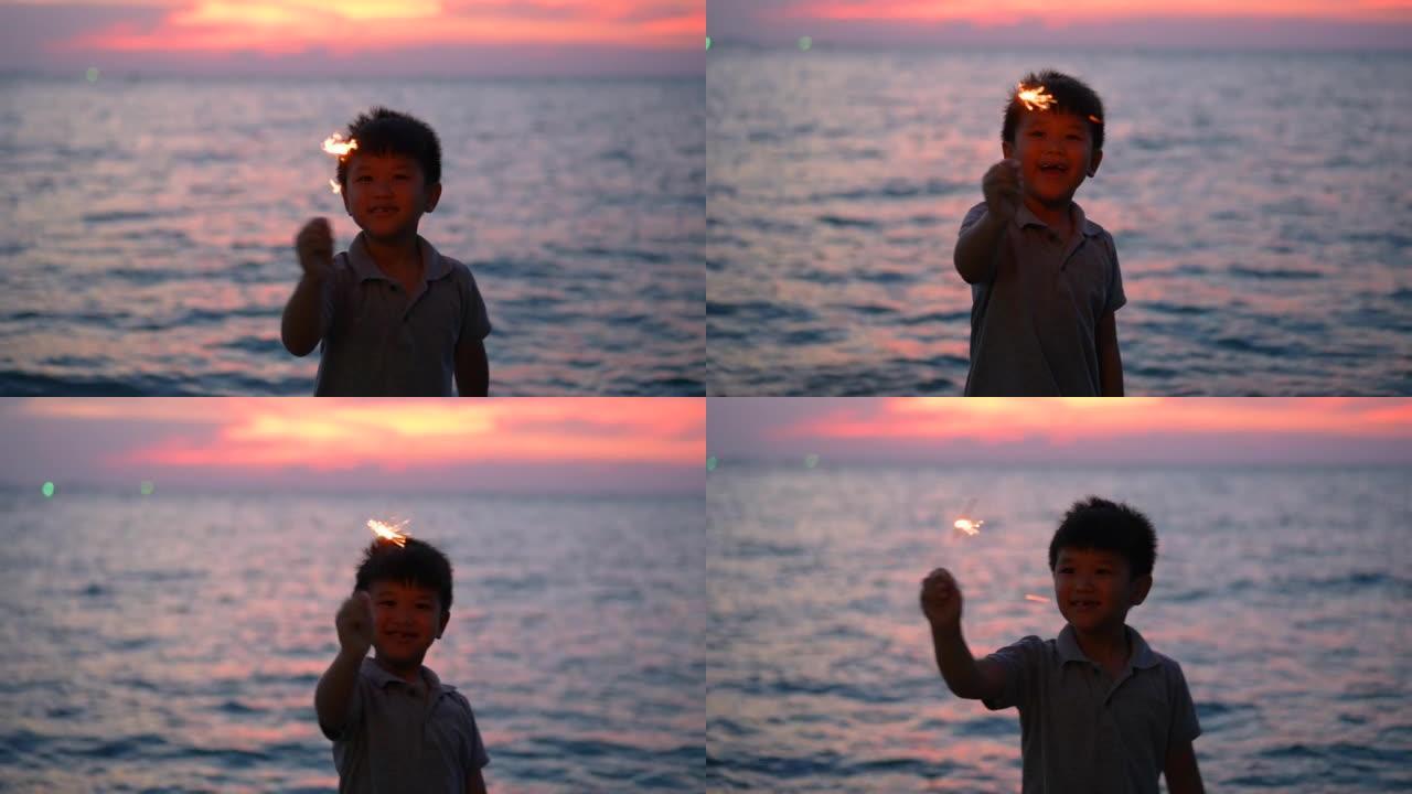亚洲男孩晚上在海滩上玩烟火。庆祝的概念