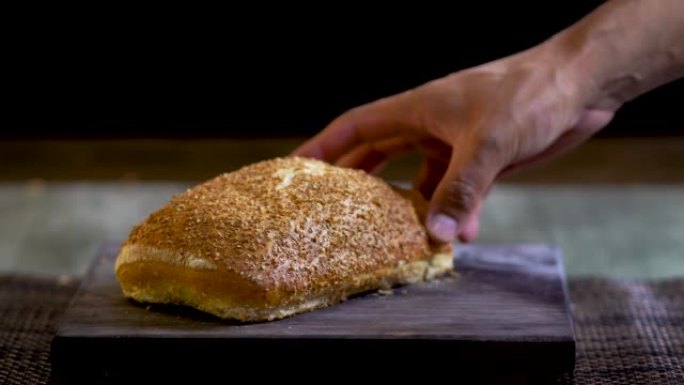 水平视频的麦麸面包，显示了一只手拿着一条新鲜出炉的面包。