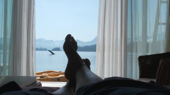 女人躺在度假床上看湖景