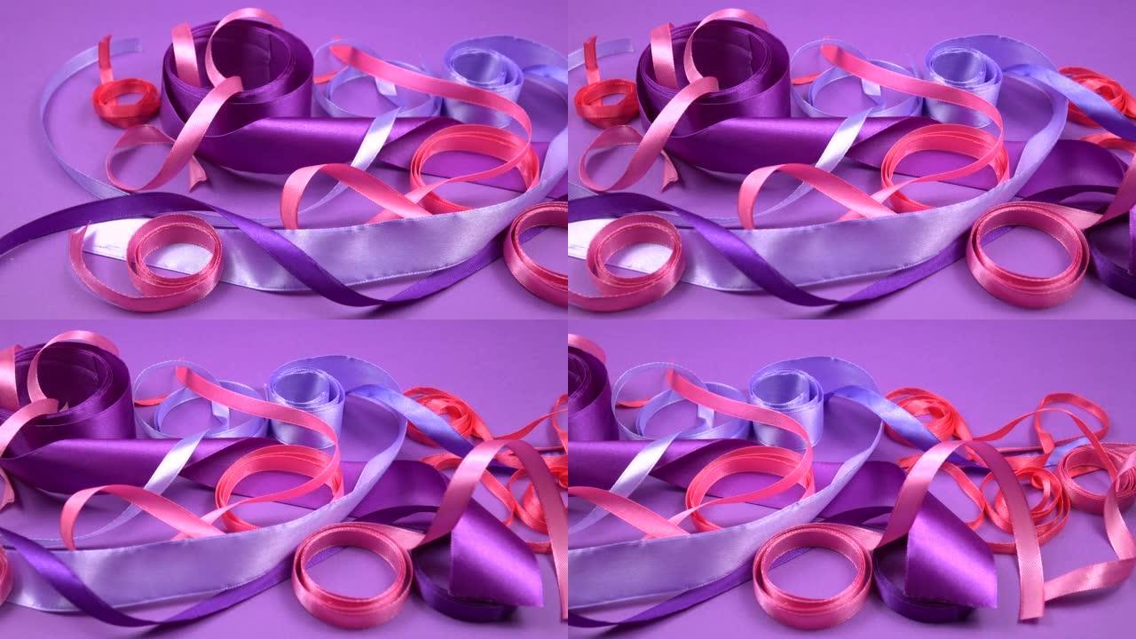 缎子紫色和粉红色丝带躺在紫色背景上