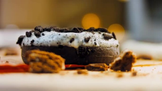 用奥利奥饼干装饰的巧克力甜甜圈。甜甜圈在用天然巧克力装饰的纸上。微距和滑块拍摄。面包店和食品概念。各