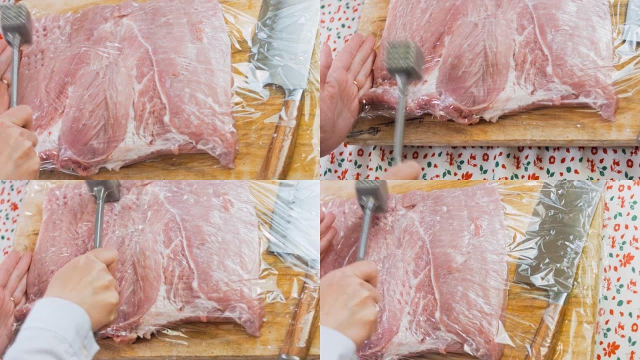 厨师用覆盖有食物箔纸的食物锤将猪肉裂片