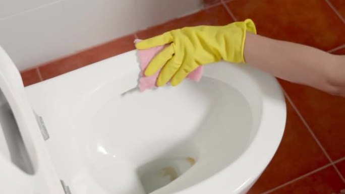 亚洲妇女用液体喷雾和粉色布擦拭厕所的手清洁马桶座圈