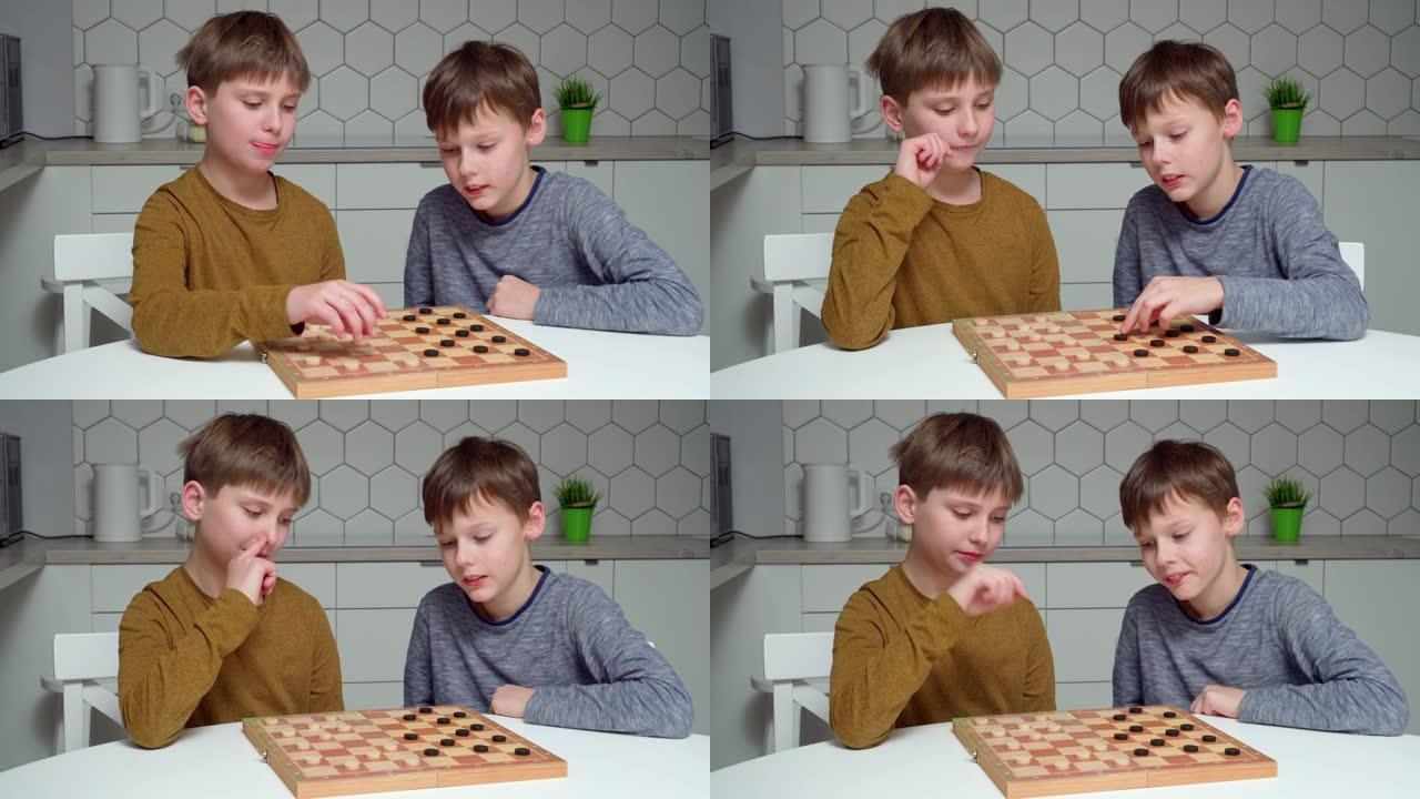视频两个微笑着感兴趣，专心的男孩在厨房的桌子上玩checkmate。战略棋盘游戏