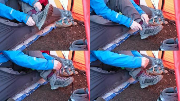 在攀登乞力马扎罗山之前，一个帐篷里的女孩坐下来穿上徒步靴。