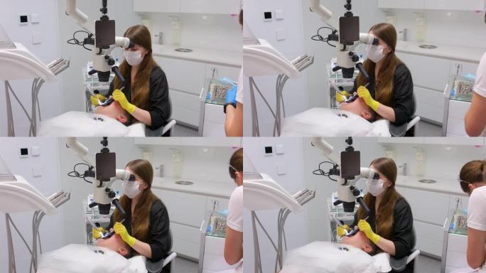 牙科诊所最新的设备和技术女医生治疗病人的牙齿使用显微镜与大平板屏幕白色背景空间文字广告黄色手套黑色衣