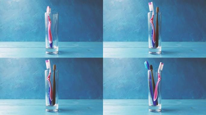 一只手将不同的多色牙刷放入蓝色背景上的玻璃特写镜头中。4k原始视频。