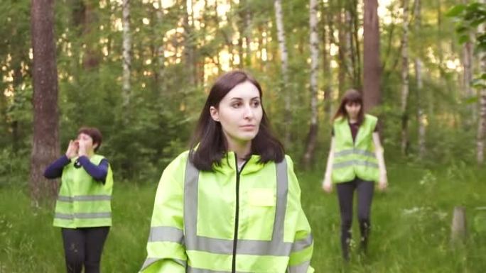 身穿绿色背心的志愿者穿过树林，寻找失踪人员的行动缓慢