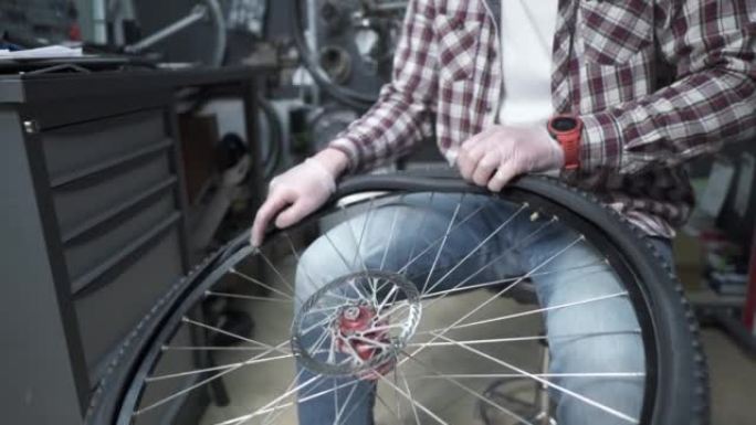 一名自行车机械师更换自行车内胎和轮胎，并在修理厂固定自行车轮。自行车轮胎保养。技术人员正在修理自行车
