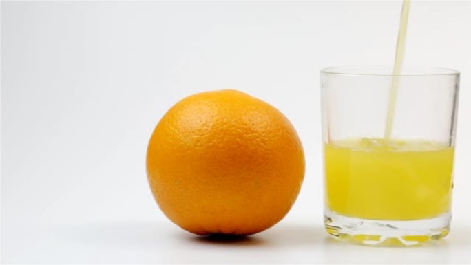 橙汁倒入玻璃杯中，白色背景上的整个橙色