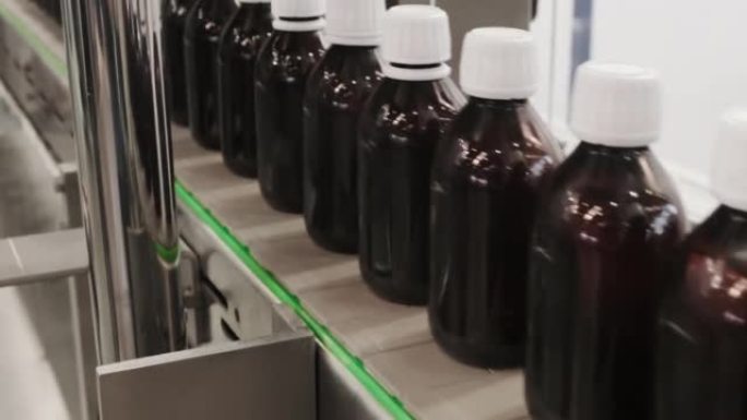 特写在制药厂4K DCI的传送带上连续包装液体药品或化妆品的许多玻璃瓶