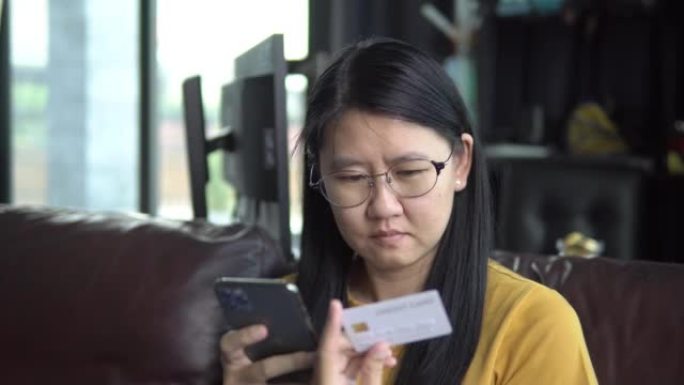 亚洲女性使用信用卡在智能手机上在线购物。