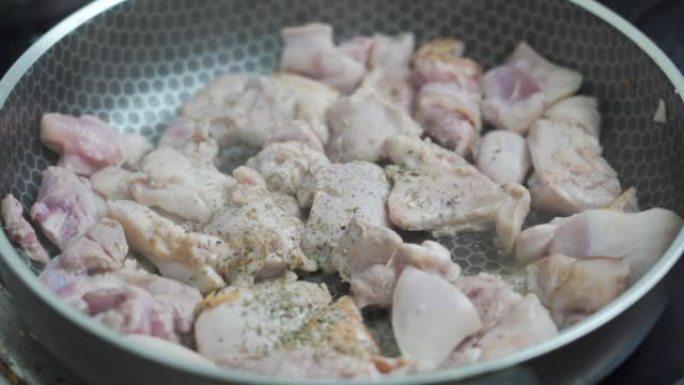 厨师在锅中煎炸的鸡大腿鱼片中添加了一小撮普罗旺斯草药