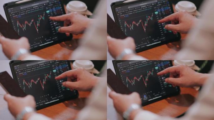投资商人的手触摸设备屏幕，看着股市图表。