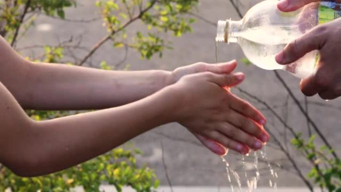 将瓶子中的水倒入孩子的手中，以洗净它们，家庭度假，儿童营地