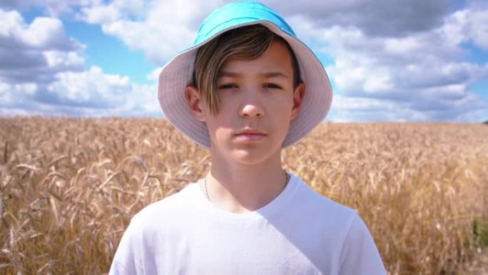 一个十几岁的男孩在麦田里看着相机的肖像，夏天阳光明媚的天气，移动的相机，steadicam镜头