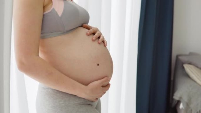 一名孕妇把手放在肚子上。怀孕期间没有妊娠纹的健康滋润皮肤。孕妇的皮肤护理。预防腹部妊娠纹