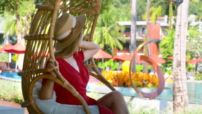 浪漫女人夏天在热带豪华度假村的竹子秋千椅上放松