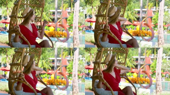 浪漫女人夏天在热带豪华度假村的竹子秋千椅上放松