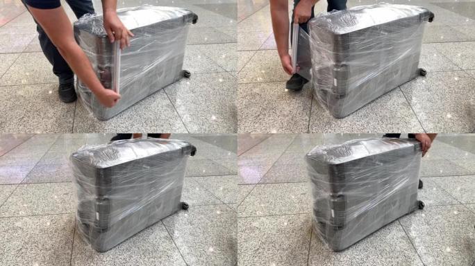 乘飞机旅行前用透明薄膜包裹手提箱的人。安全或安全保护概念。在机场航站楼打包行李