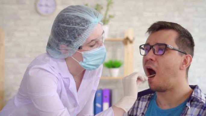 在现代诊所里，一名女性实验室技术人员用棉签从一名男性嘴里提取唾液进行测试