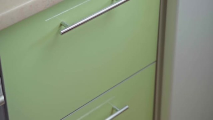 男人用手打开厨房橱柜门，在里面挨着架子拿锅。关闭带玻璃门的现代厨柜，用于存放干净的餐具