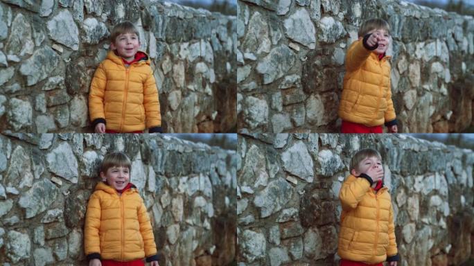 石墙前的蹒跚学步的男孩向镜头致意