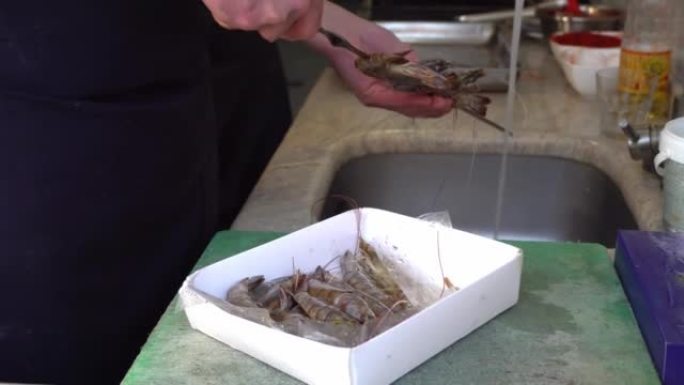 厨师的手专业地把国王虾串在串上，以便进一步准备。