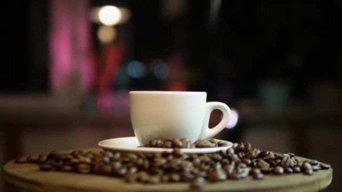 带蒸汽的热咖啡在窗外夜城的散景背景下，在咖啡馆的酒吧里喝咖啡，杯子里冒烟。