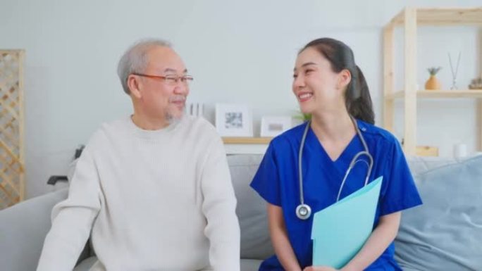 亚洲护理员护士的肖像坐在沙发上照顾老人。有吸引力的专业护理妇女支持老年成熟的祖父在养老院护理和微笑，